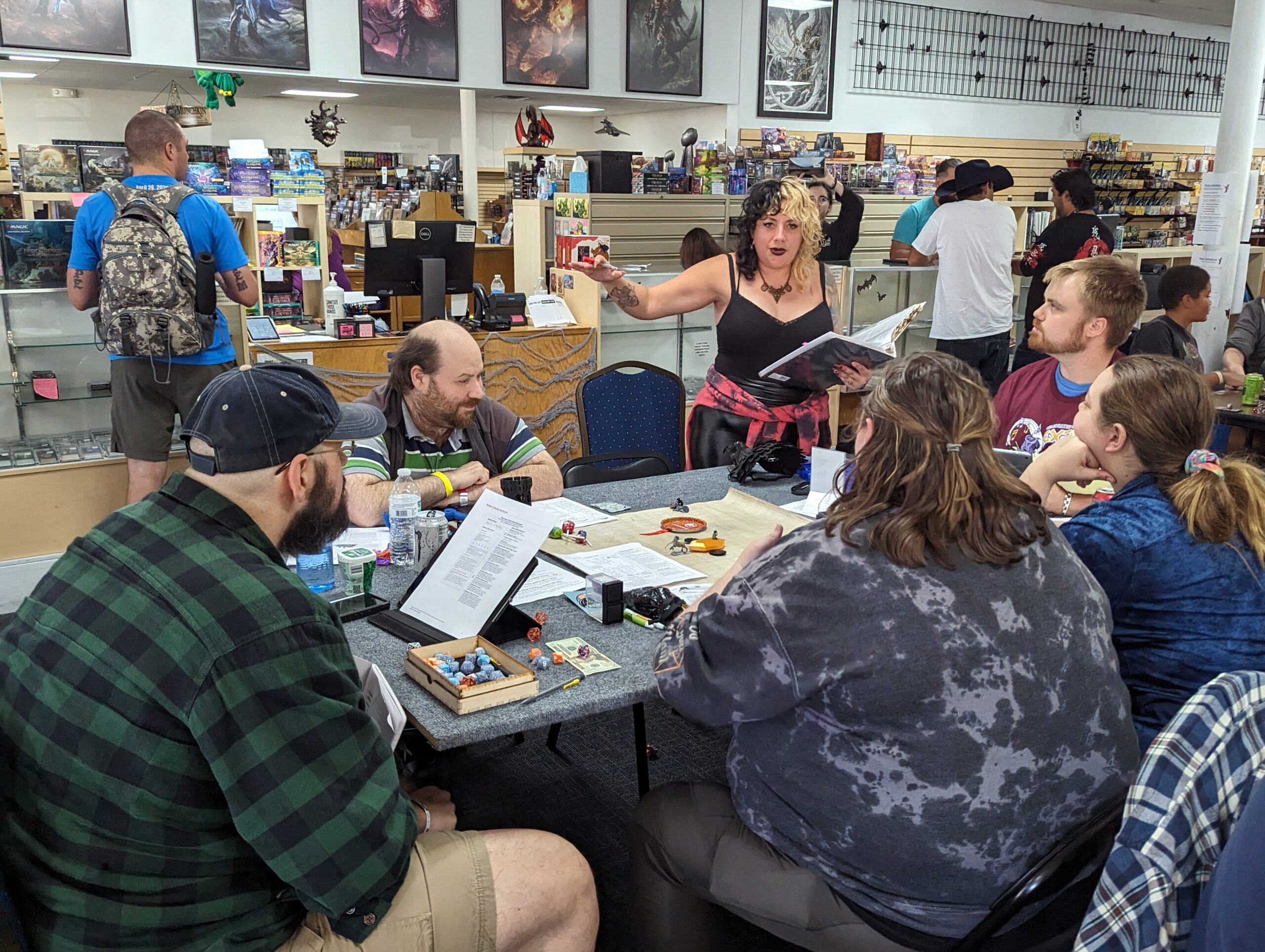 non-profit-05 A woman stands while animatedly playing a game of D&D with a 5 other people around the table looking at her.